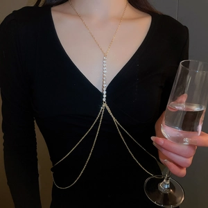 Detailed view of luxury gold body chain with crystal tassels worn on a black V-neck outfit