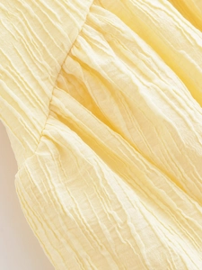 Macro view of light yellow pleated fabric with distinct tree bark texture and soft sheen
