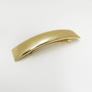 Macro detail of golden metal spring clip with horizontal textures and a curved design