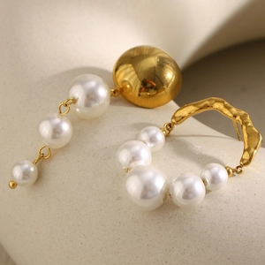 French vintage style gold earrings with imitation pearls on a beige texture background