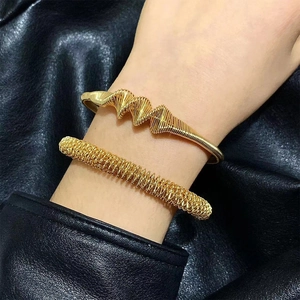 Bracelets manchettes dorés avec designs géométriques en spirale et effet ressort