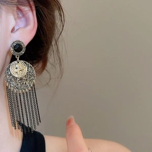 Detail of vintage gold earrings with portrait coin, black stones, and long chain fringe