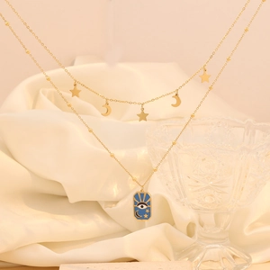 Close-up of double-layer gold star moon necklace with blue evil eye pendant on silk