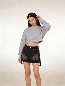 Detail of black washed denim cargo skirt with large utility pockets and ribbon straps