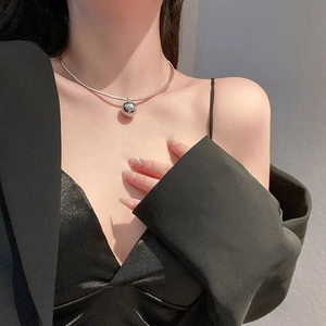 Detailed close-up of a minimalist silver ball choker on a model's collarbone area