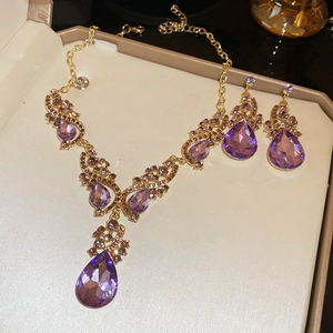 Detailed shot of vintage gold jewelry set with teardrop purple crystals in a gift box