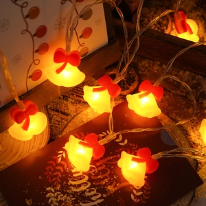 Close-up of LED Christmas bell lights with red bows on a festive wooden surface