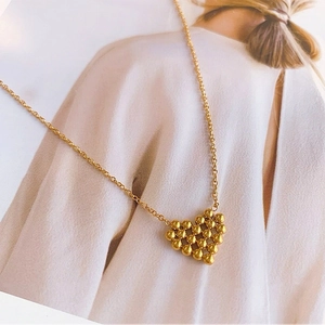 Gros plan d'un collier avec pendentif cœur doré en perles sur un mannequin en blanc