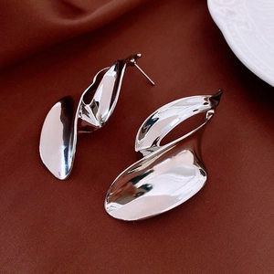 Close-up of silver bow tassel earrings with a polished abstract streamline metal finish