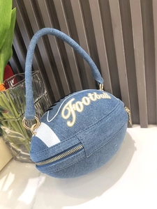 Detail of rugby-shaped blue denim handbag with golden Football embroidery and zipper