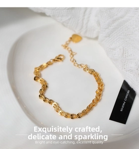 Detail of gold woven chain bracelet with a heart pendant on white ceramic display