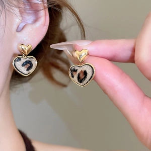 Primo piano di orecchini a cuore placcati oro 18K con stampa leopardata su una modella
