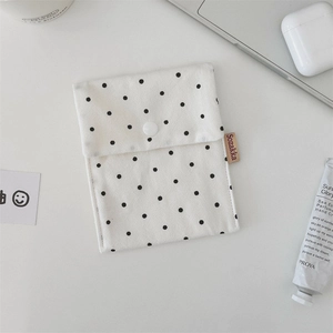 Close-up of white polka dot canvas storage bag with button closure and brand woven label