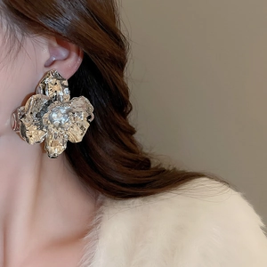 Macro detail of large oversized metallic flower stud earrings in shiny silver finish