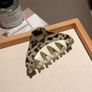 Detail view of a triangle leopard print hair claw clip on a stylish wooden tray