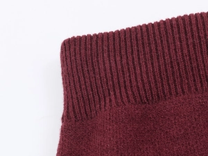 Gros plan sur le tricot côtelé du poignet et de l'ourlet du pull de couleur bordeaux