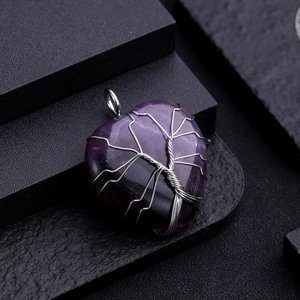 Close-up of tree of life pendant with purple heart gemstone and silver wire wrapping