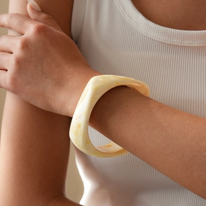 Close-up of a resin bangles bracelet featuring creamy marble texture on female wrist