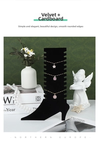 Close-up of black velvet boot jewelry stand displaying three gold necklaces with pendants