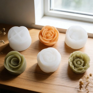 Dettaglio di stampi in silicone a pivoine e candele in resina su tavolo in legno
