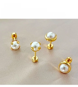 Detailed view of pearl earrings with gold screw backs and prong settings on satin fabric