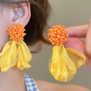 Detailed macro view of orange beaded stud with yellow chiffon fabric petal tassels