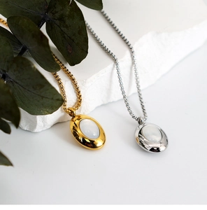 Close-up of gold and silver oval shell necklaces on a white textured stone surface