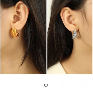 Detailed close-up of chunky ribbed spiral earrings in polished gold and silver finishes