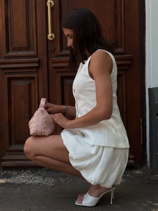 Détail d'un ensemble deux pièces blanc sans manches avec un sac tressé rose et talons
