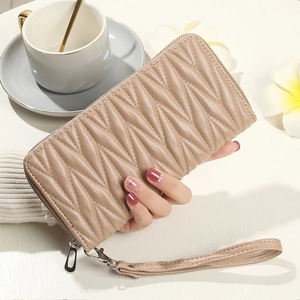 Close-up of beige quilted leather clutch wallet with silver zipper and wrist strap