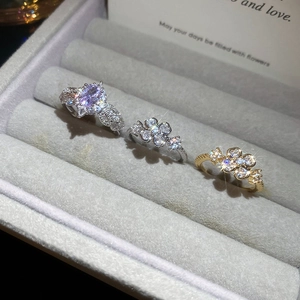 Close-up of three elegant floral zircon rings presented in a gray velvet jewelry box