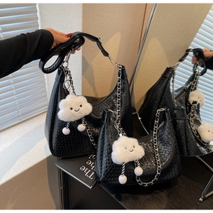 Close-up of black woven shoulder bag with metal chain strap and white cloud pendant