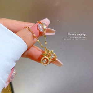 Macro view of 18K gold cherry necklace with dancing white zircon stones on a fine chain