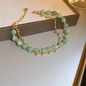 Detail of double-layer gold-plated bracelet with light green jade beads and heart charm