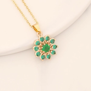 Detailed close-up of gold flower pendant with vibrant green cubic zirconia inlay