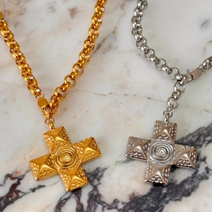 Detail of 18k gold and silver cross necklaces with studded texture on marble
