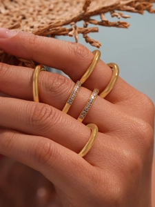 Macro detail of layered gold-plated rings with CNC-set 5A cubic zirconia stones on hand