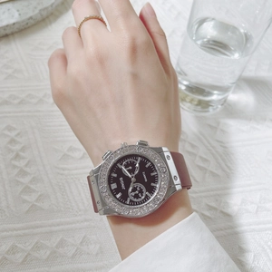 Close-up of stylish silver rhinestone watch with red silicone strap on a wrist
