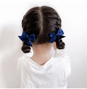 Close-up of deep blue satin bow hair clips on a young girl's braided hairstyle