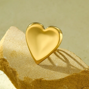 Polished 18K gold heart-shaped open ring displayed on a natural rock surface