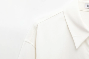 Detail of white cotton twill shirt collar with reinforced stitching and woven label