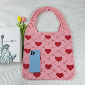 Close-up of pink knit tote bag with red heart pattern and diamond mesh texture