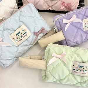 Macro view of quilted macaron colored vanity bags with ribbon bows and corduroy handles
