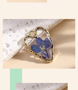 Close-up of heart resin pendant with blue dried flower and elegant gold frame