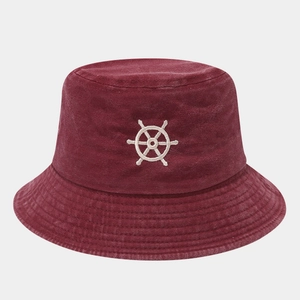 Close-up of a burgundy cotton bucket hat featuring white nautical helm embroidery