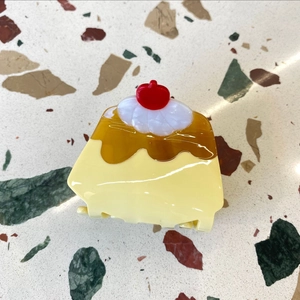 Detailed view of a cute pudding-shaped hair claw clip with cherry and cream accents