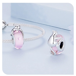 Macro shot of silver cat charm with pink glass bead and heart zircon on a snake chain