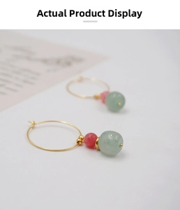 Detail of gold hoop earrings with translucent green and matte pink beads in vintage style