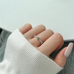 Detailed view of silver rings featuring green four-leaf clover motifs and zircon stones