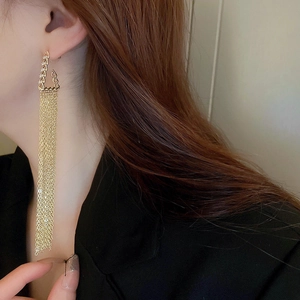 Close-up of golden multi-layer chain tassel earrings with sparkling zircon on a model